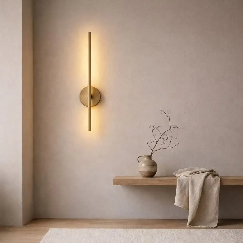Modern wall sconce on a neutral wall with a wooden shelf and decorative items.