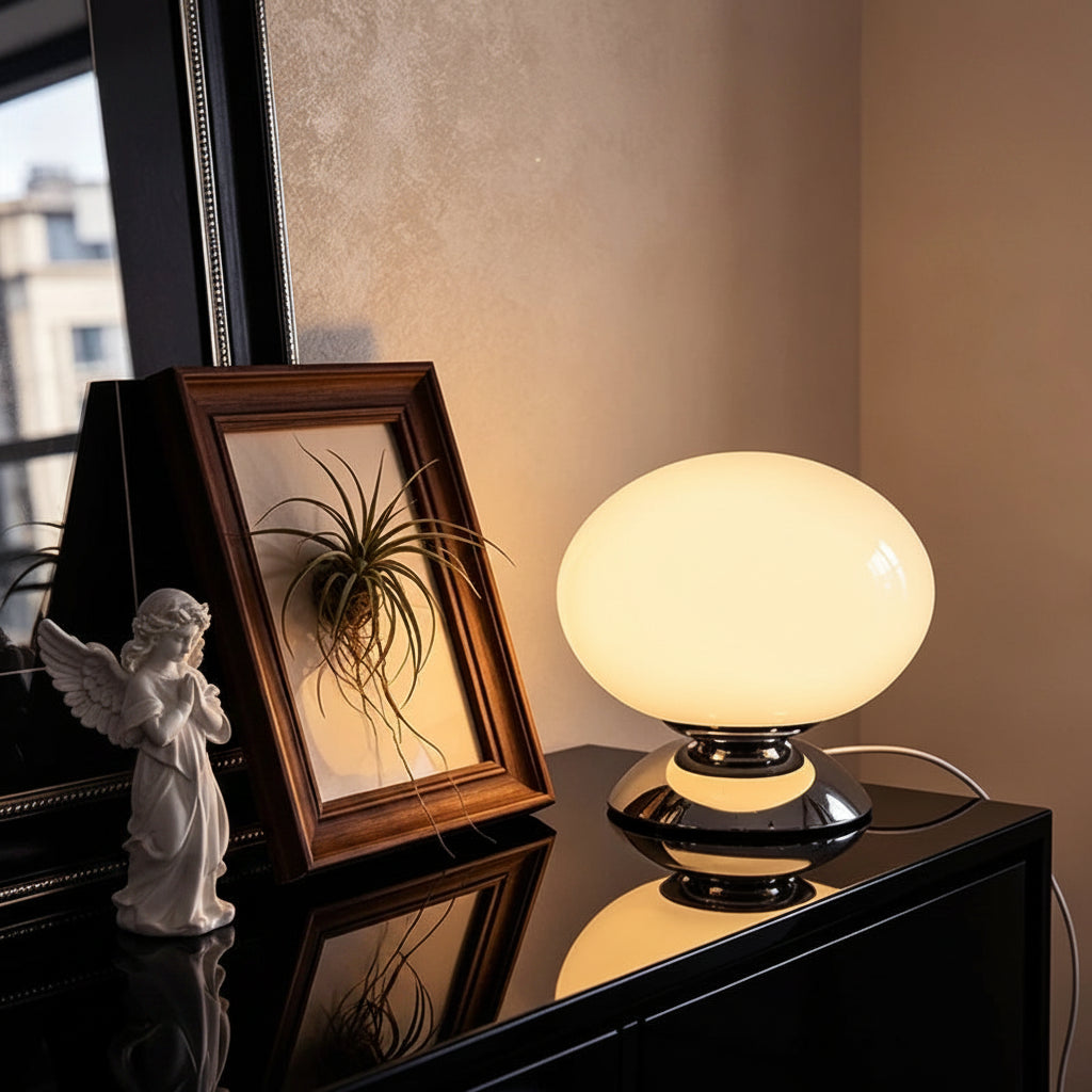 A glass globe shell lamp with a warm glowing oval shade and glossy black base, shown on a dark cabinet in an indoor setting. Text overlays read 'Glass Globe Shell Lamp', 'Usb Power Plug', and '3 Color Temperature', with a circular logo for 'Jeda Home Lighting'.