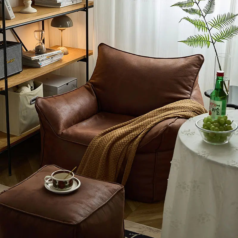 Cozy living room with brown leather armchair, ottoman, and a small table with a bowl of grapes.