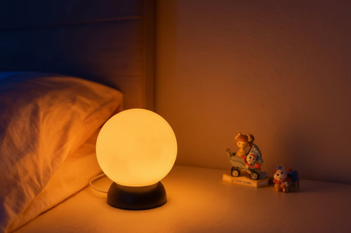 Round lamp on a bedside table with toys in the background